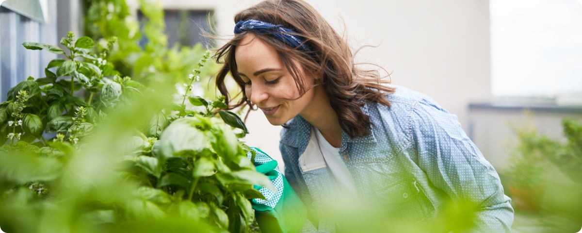 Frau im Garten riecht an Blumen