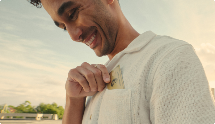 Mann zieht die Gold Card aus Metall auf seiner Hemdtasche