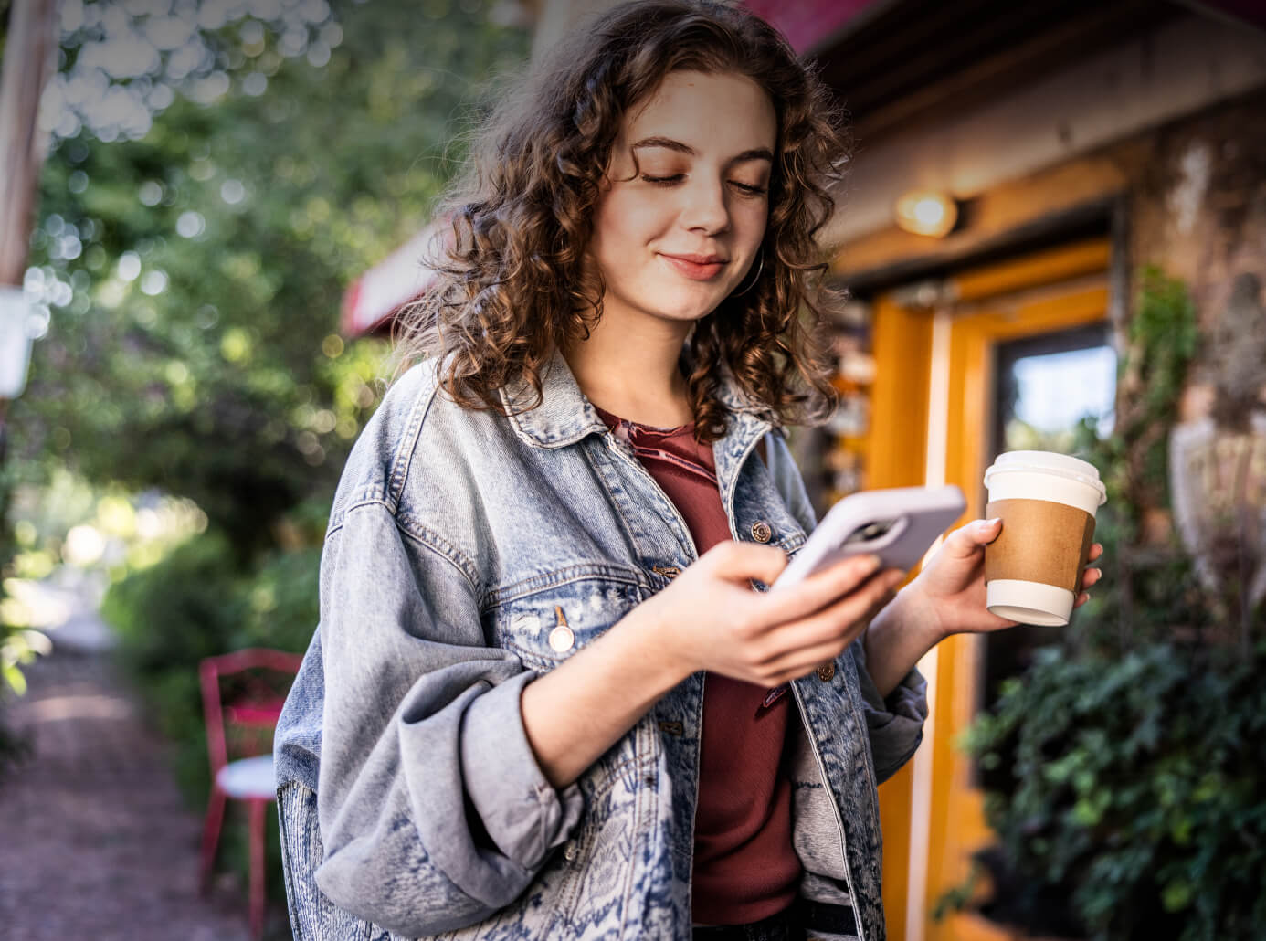 Junge Frau mit Handy und Kaffee in der Hand